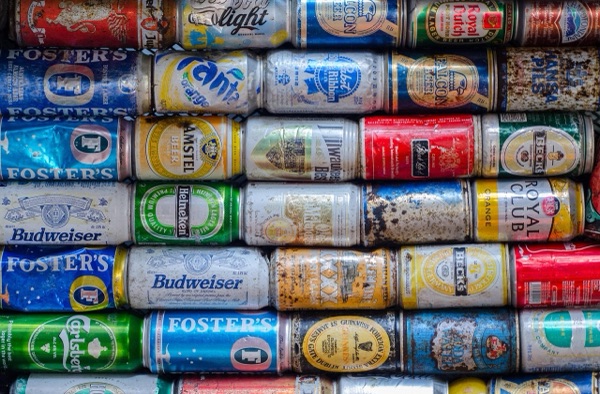 A wall of crushed and stacked beer cans of many brands